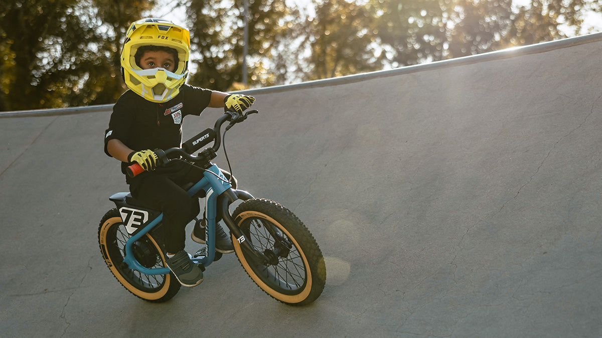 A young child on a SUPER73-K1D ebike wearing a full face helmet