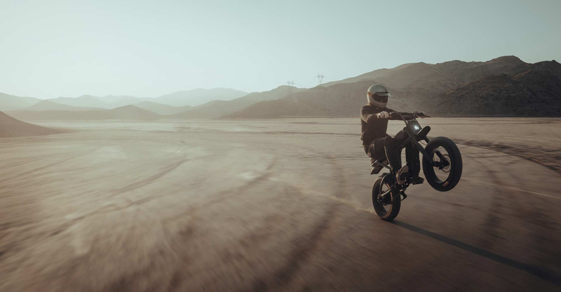 A SUPER73 rider having a blast riding out in an open area while wearing a helmet.