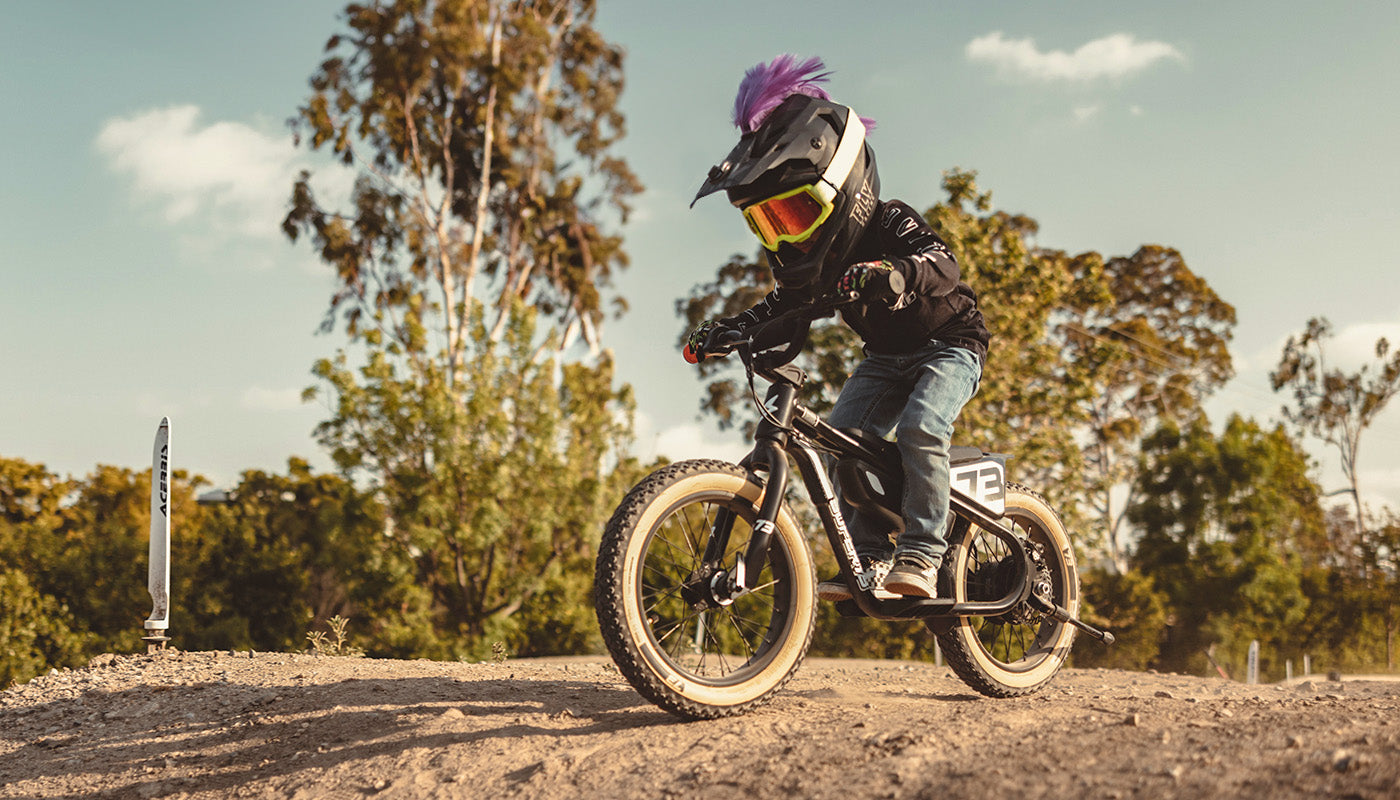 A young child on a SUPER73-K1D ebike wearing a full face helmet