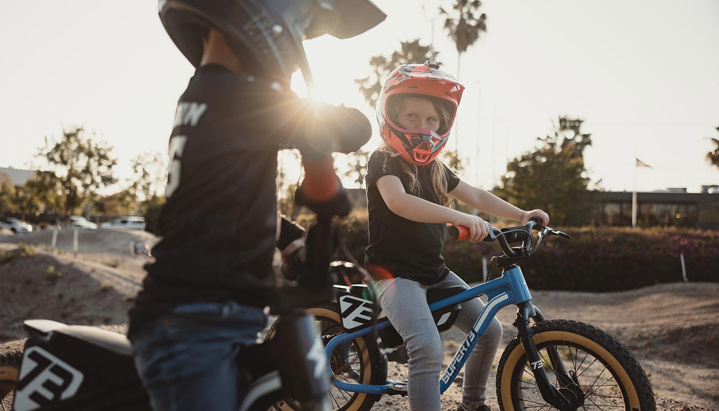 A couple of kids getting ready to ride their K1D balance bikes on a dirt track.