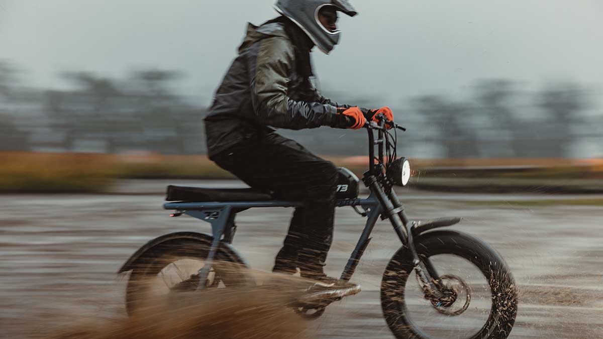 Young man riding a SUPER73 S2 ebike through mud on a rainy day