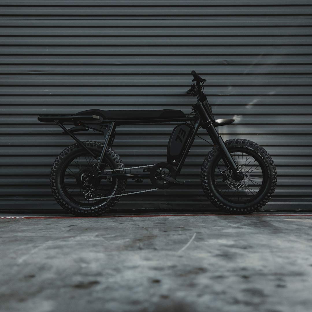 Image of a SUPER73-S Blackout SE bike parked in front of a warehouse door.