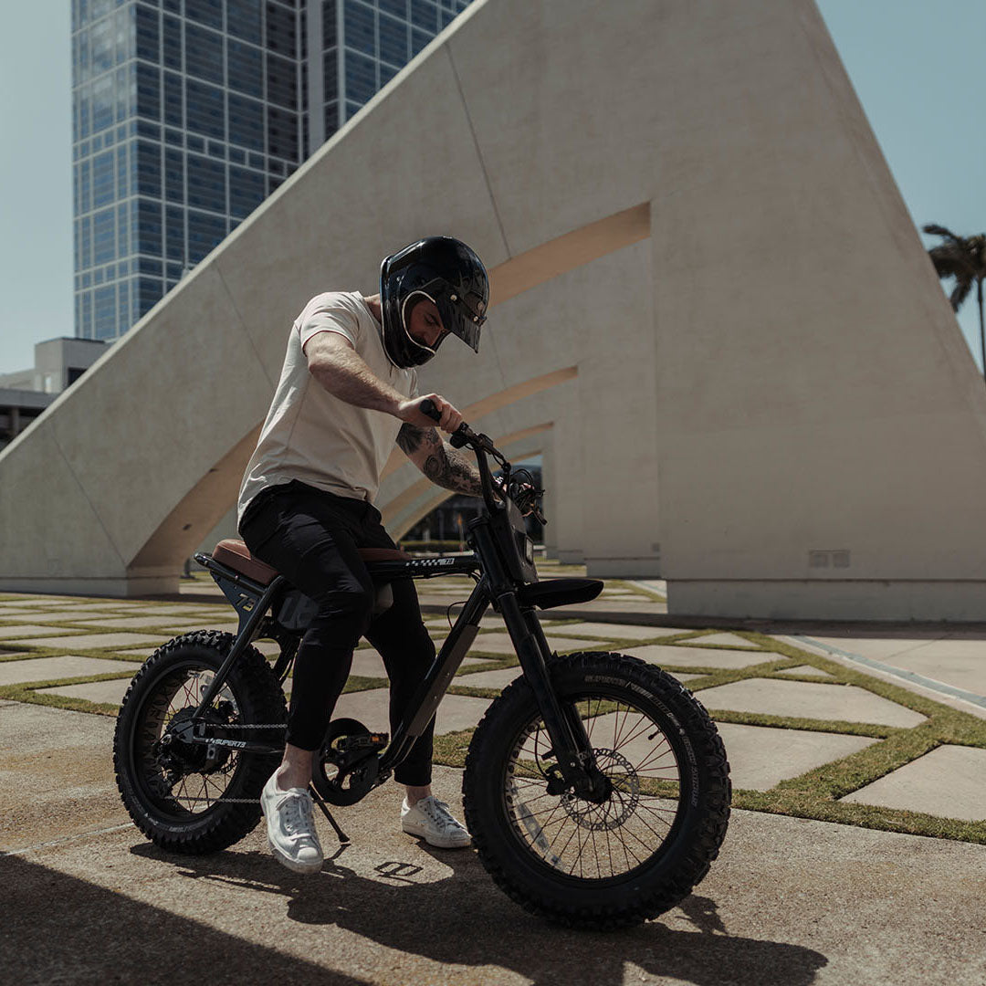 Lifestyle image of a man in a helmet sitting on a SUPER73-Z Adventure SE ebike in Palladium