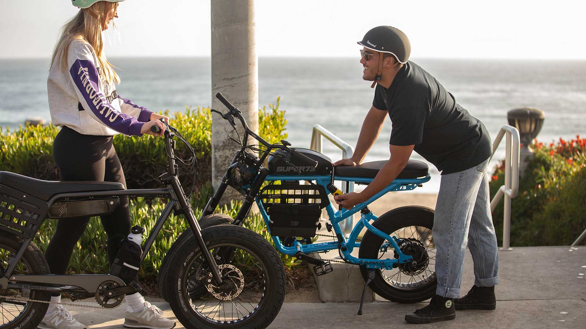 Man on the beach using a hand tool to tighten a bolt on his bike