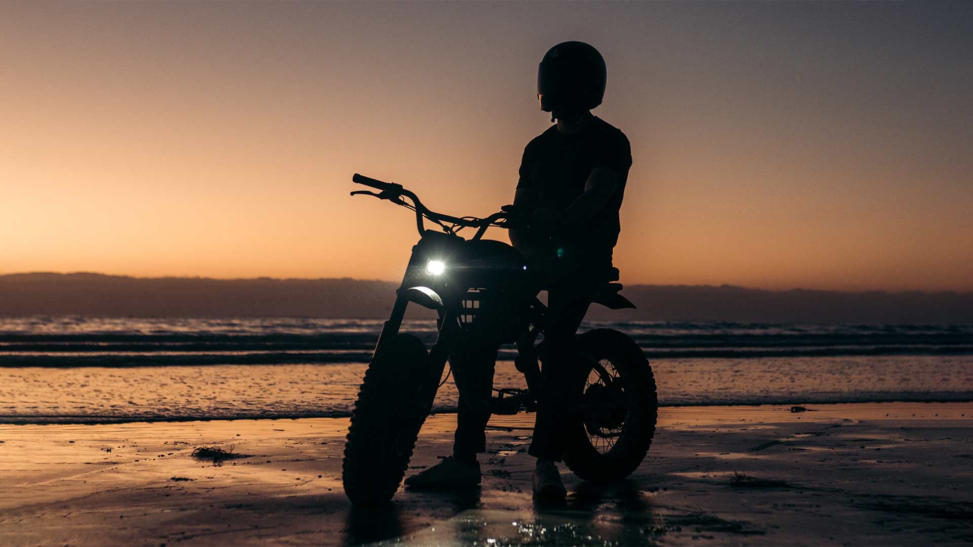 Dark silhouette of Super73 ebike on the beach at sunset.