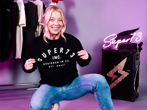 Lifestyle image of a woman wearing a branded SUPER73 crew neck sweatshirt.