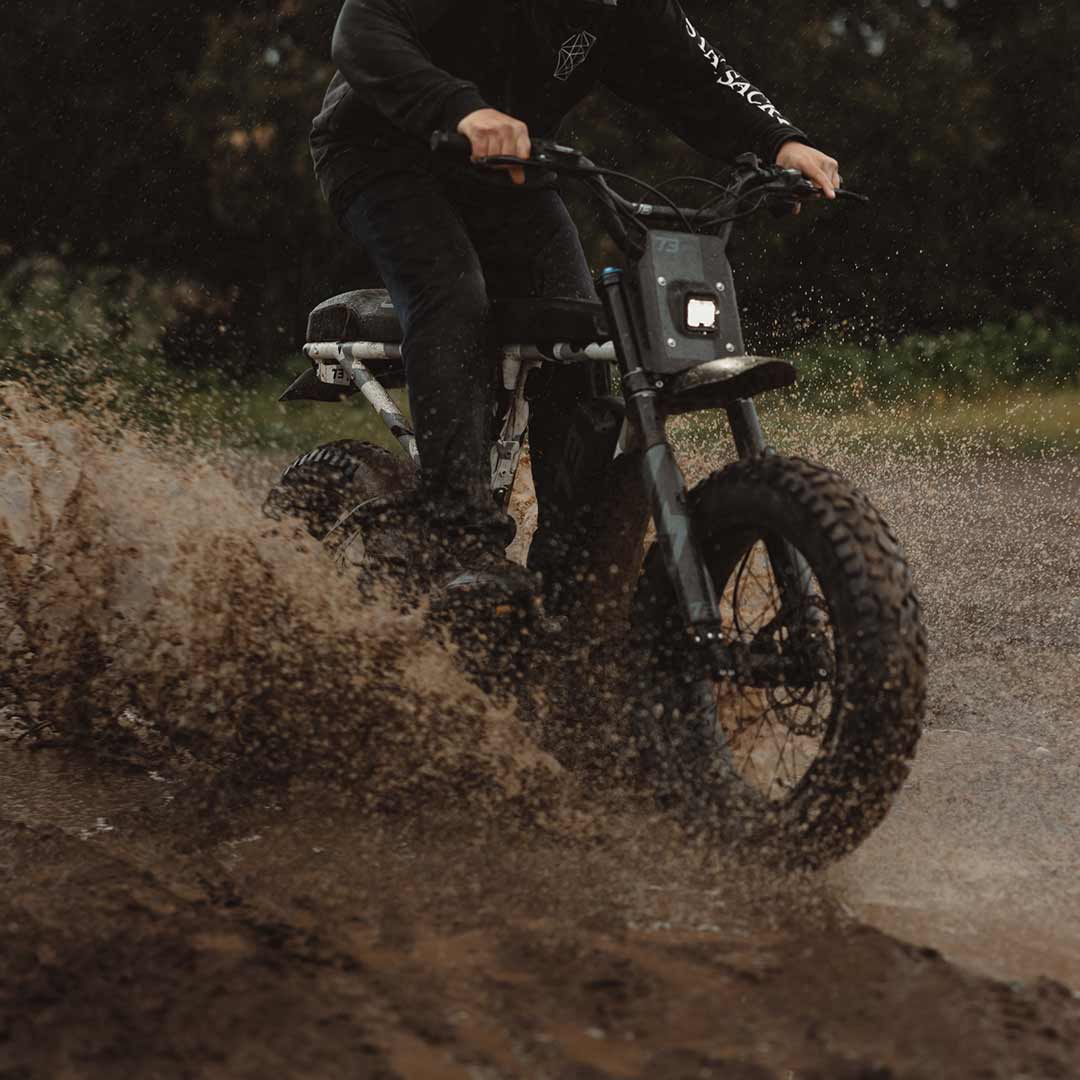 Lifestyle image of a rider riding the R Adventure through a muddy path and wearing a helmet.