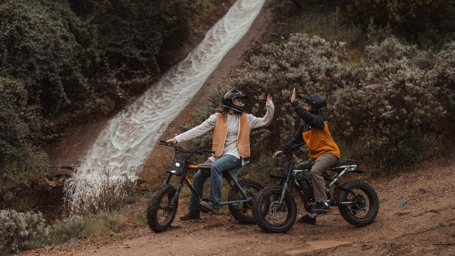 Riders on Super73 ebikes in front of waterfall.