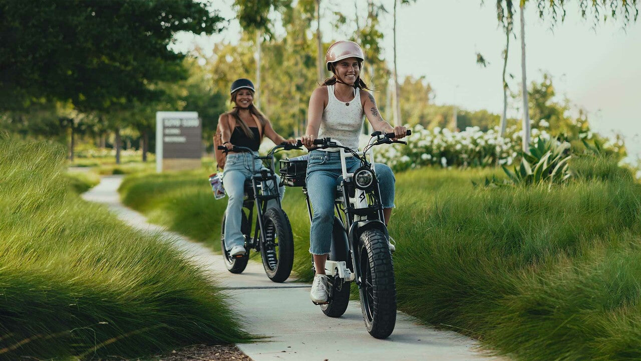 Riders wearing helmets enjoying a paved bike path