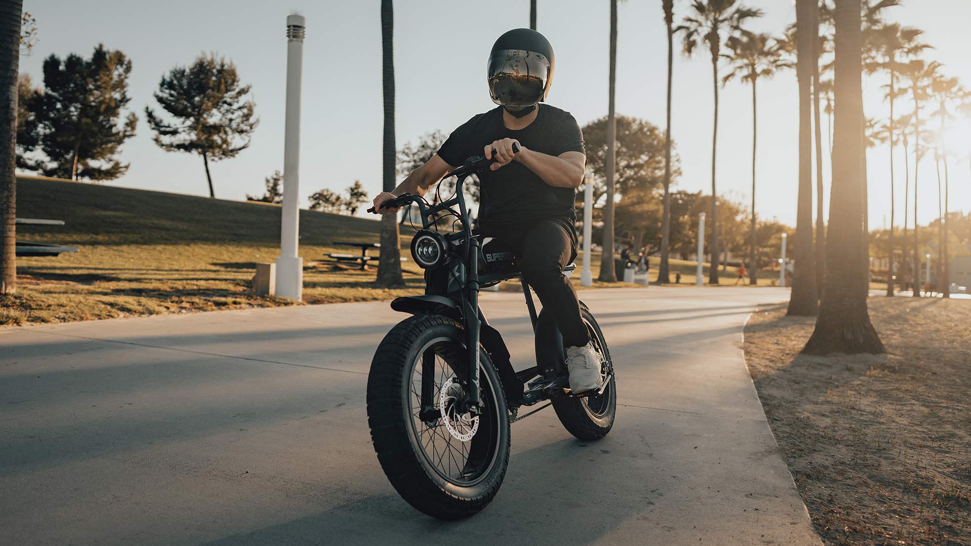 Lifestyle image of a recent grad riding his SUPER73 S2 near the beach.