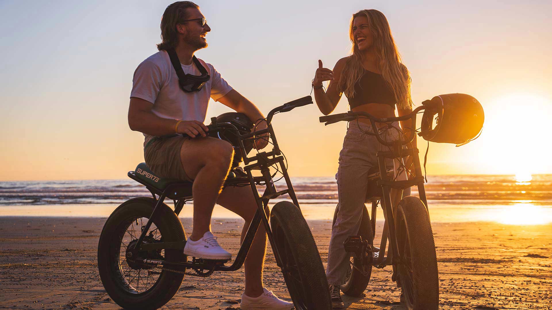 Two riders enjoying the sunset on the beach with their SUPER73 e-bikes