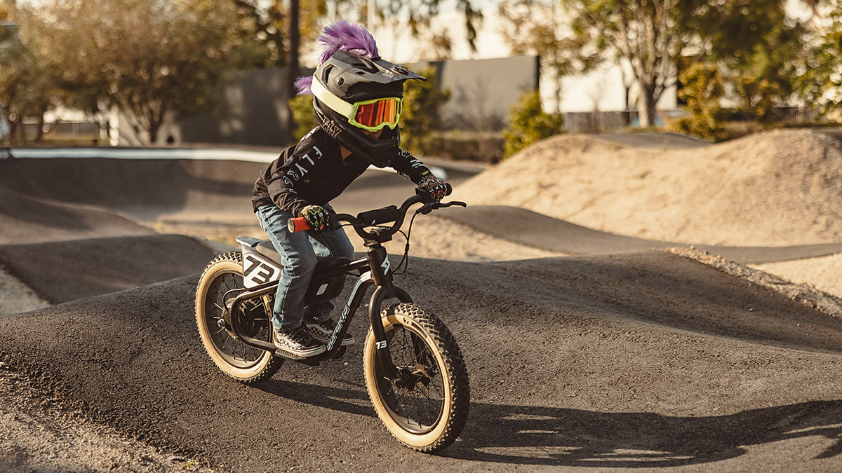 A young child on a SUPER73-K1D ebike wearing a full face helmet that has a mohawk