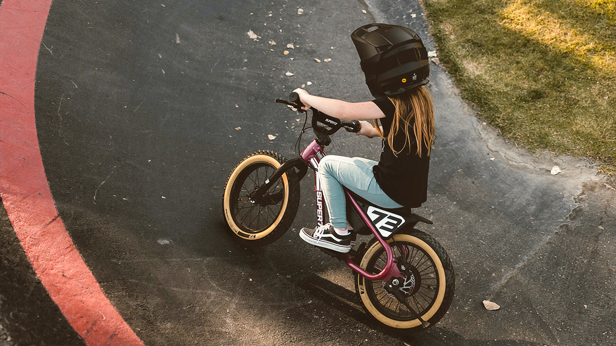 A young child on a SUPER73-K1D ebike wearing a full face helmet