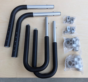 The full contents of the MBB Dual Sport Surf Rack package sits on a light colored wooden table. All necessary hardware is included in the box.