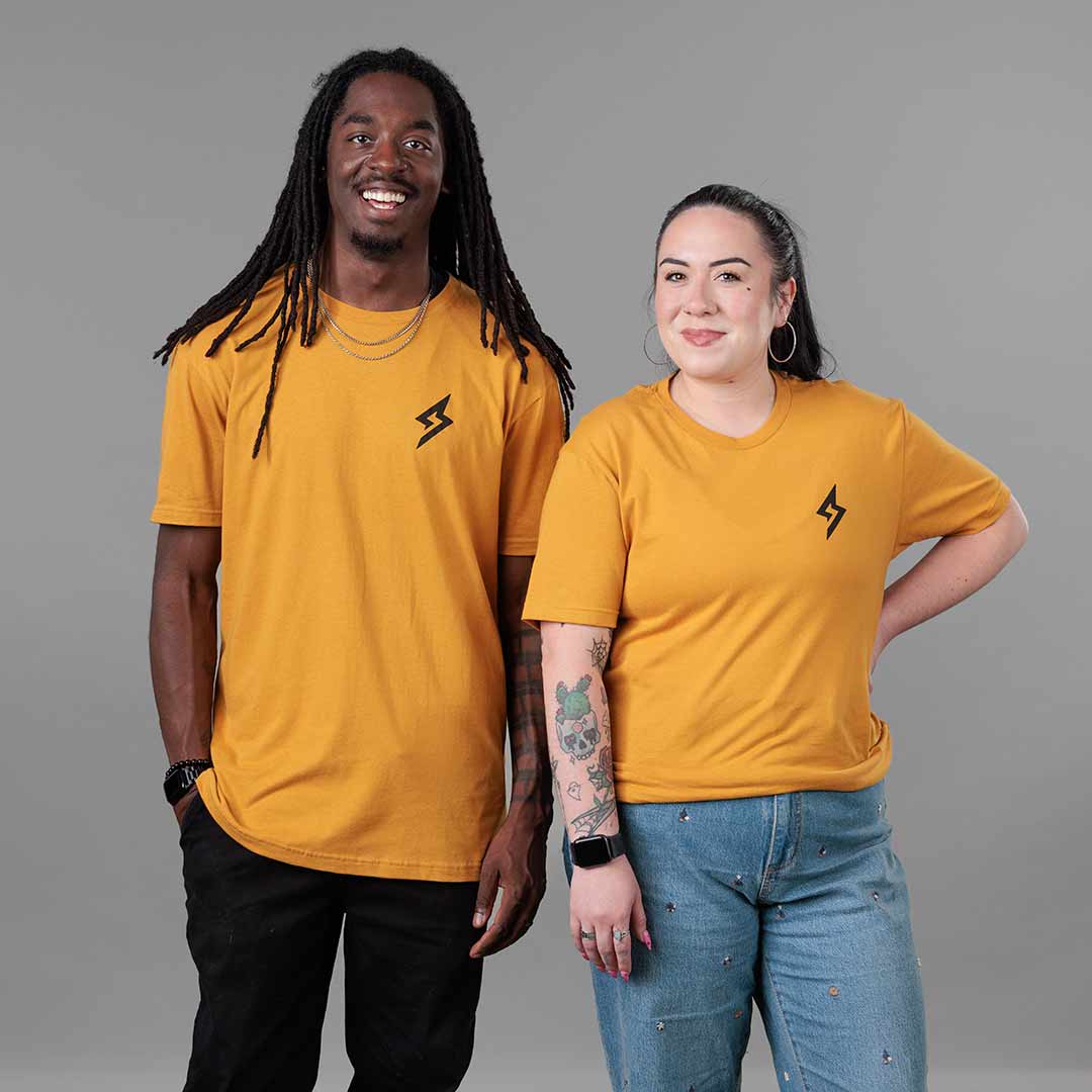 Studio image of The Trailblazer Tee (Antique Gold) on both male and female models 