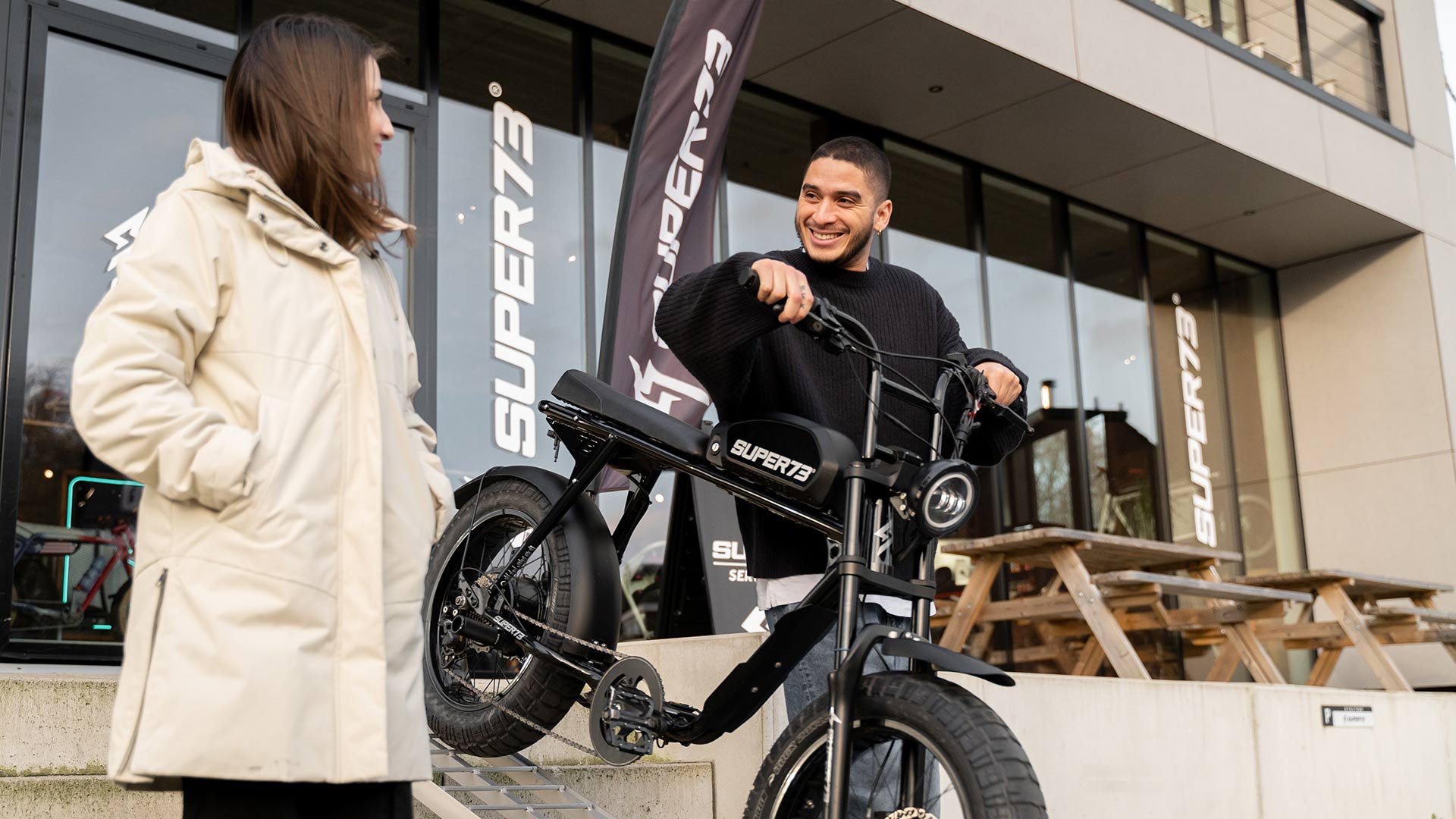 Man and woman standing with SUPER73 bike outside of a retail location.