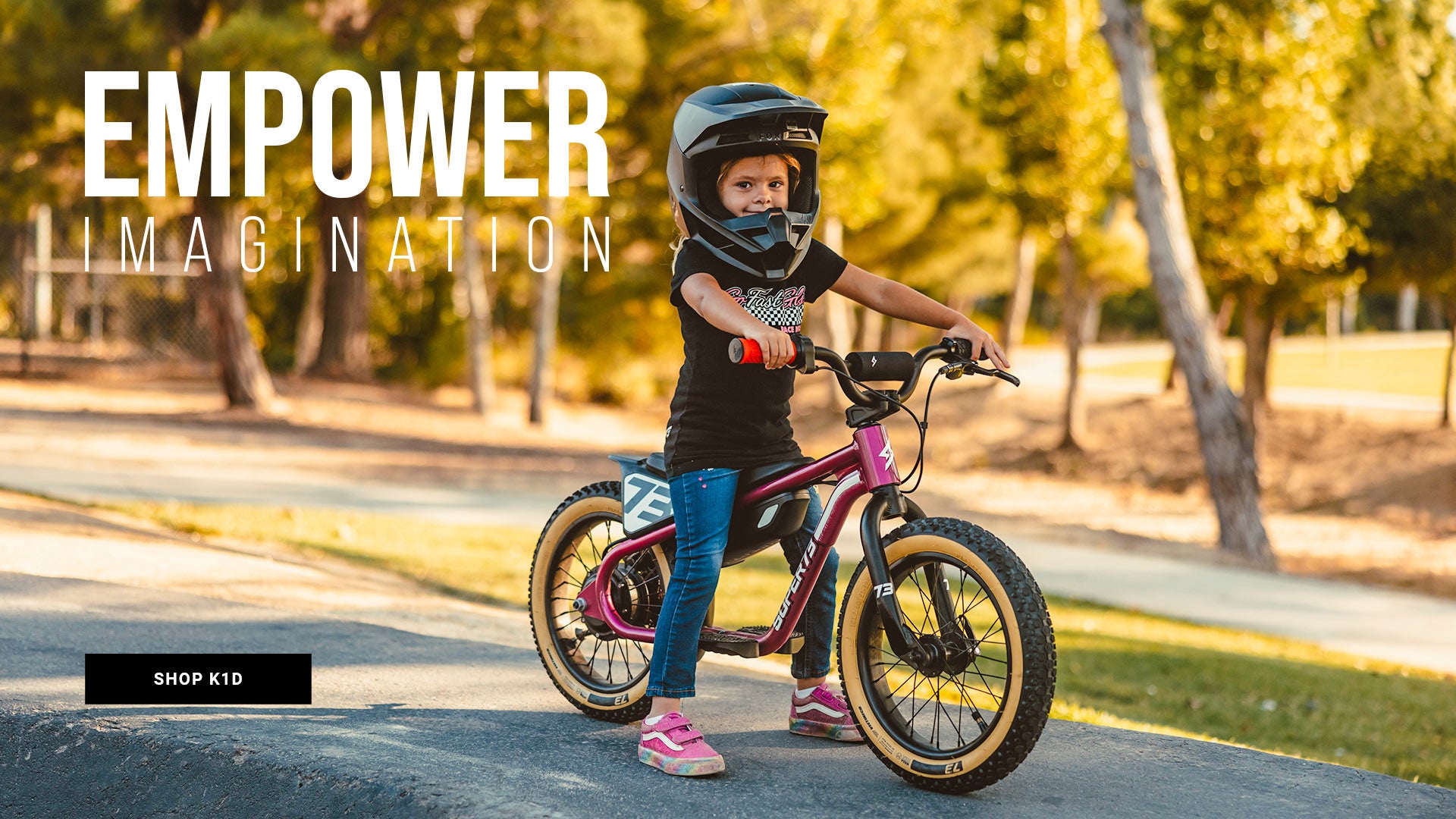 Lifestyle image of a young girl in a helmet riding a SUPER73-K1D ebike in Prickly Pink