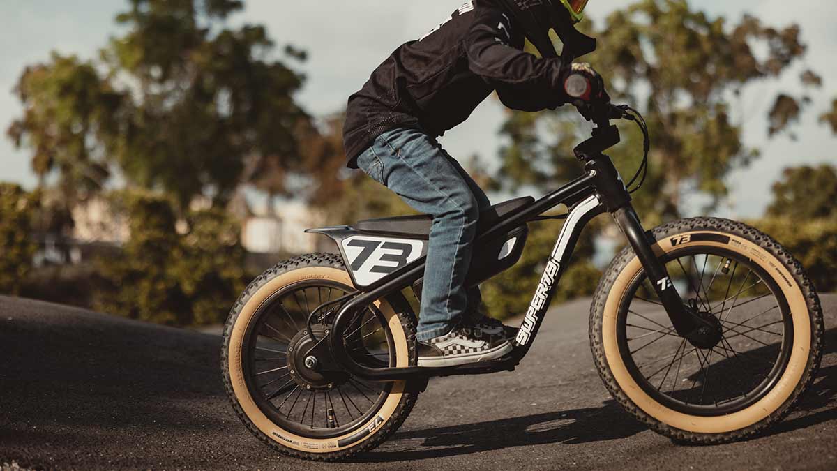 Young rider on his black SUPER73 K1D kid's e bike on a paved pump track 