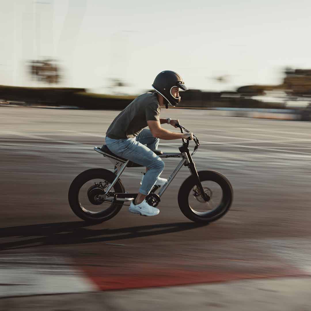 A rider cruising by on his super73 metallic aluminum zx with a helmet on