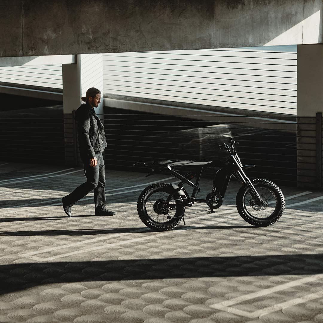 Image of a man in a parking garage walking toward the SUPER73-R Blackout SE bike.
