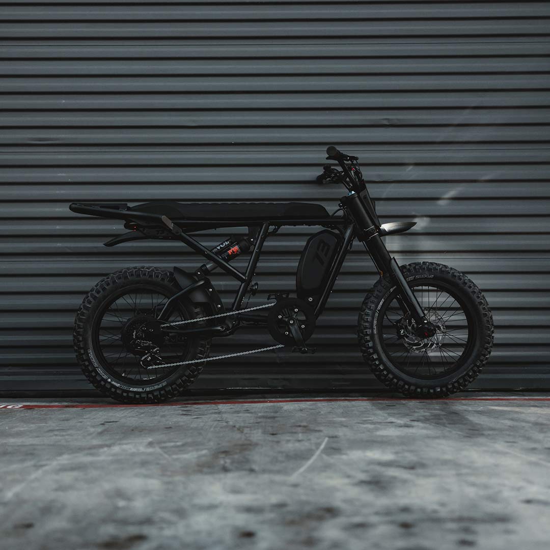 Image of the SUPER73-R Blackout SE bike parked in front of a warehouse door.
