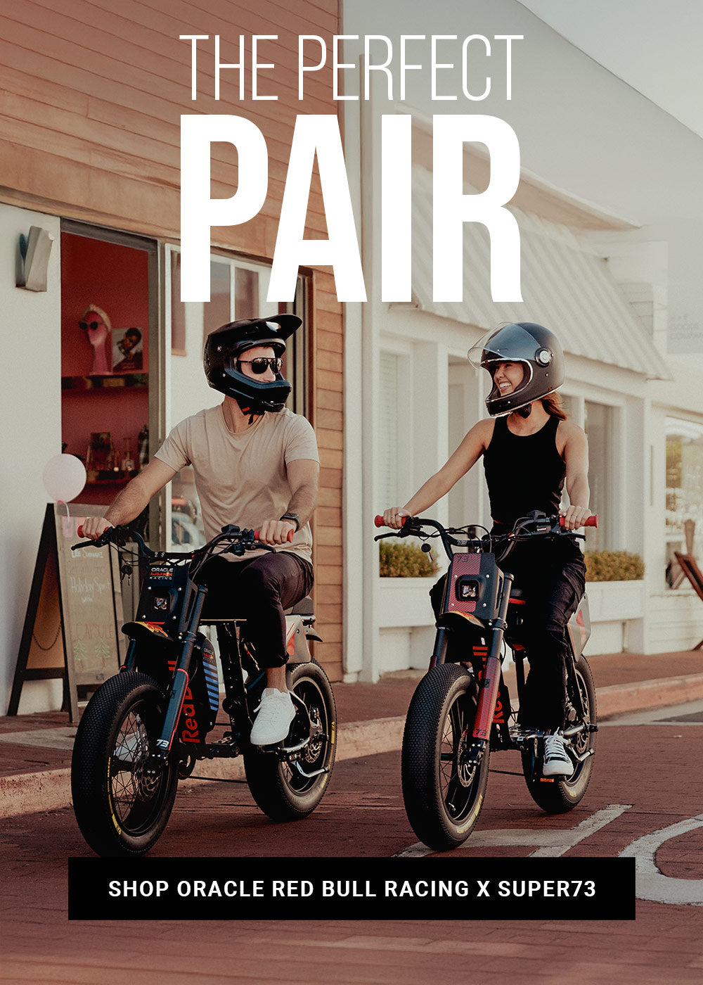 Lifestyle image of a man and woman in helmets riding the Oracle Red Bull Racing R Adventure Series and Z Adventure Series ebikes along a paved road.