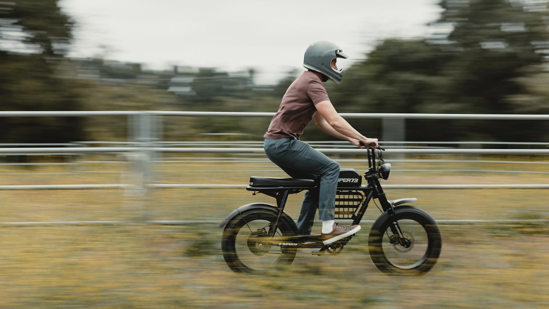 Young man riding his SUPER73 S2 ebike through a flower field full throttle with a helmet on