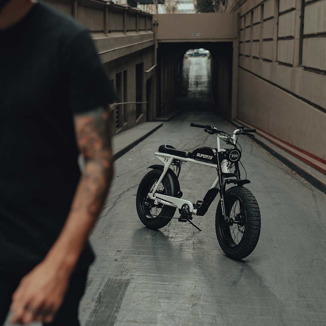 Man out of focus walking away from a SUPER73 S2 ebike sitting in an alley