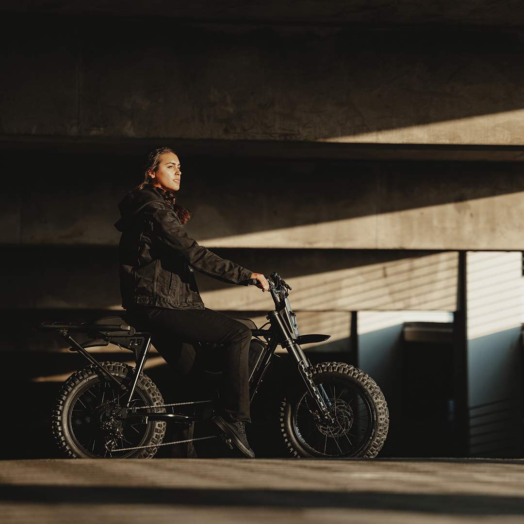 Image of a woman riding a SUPER73-S Blackout SE bike in a parking garage.