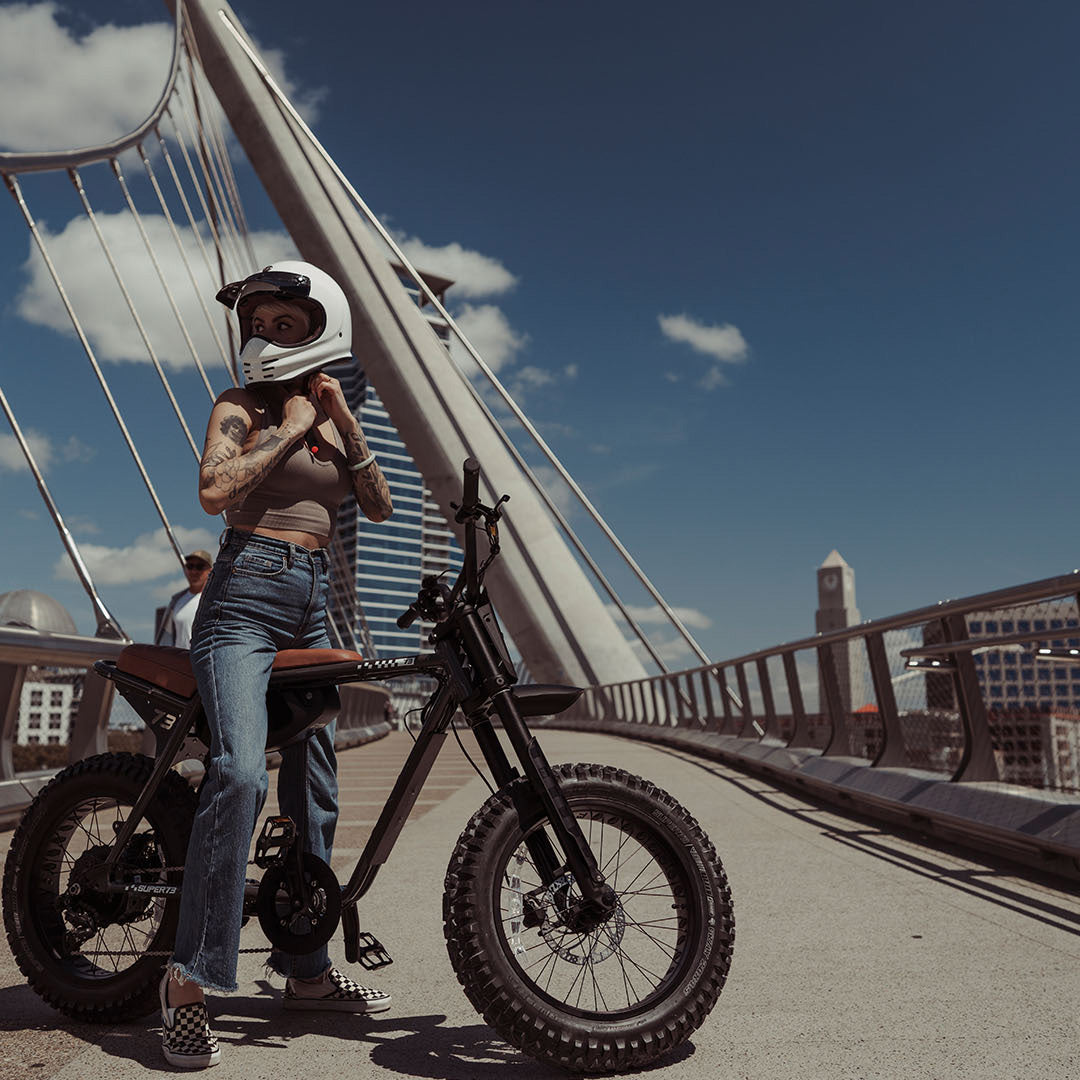 Lifestyle image of a woman in a helmet sitting on a SUPER73-Z Adventure SE ebike in Palladium