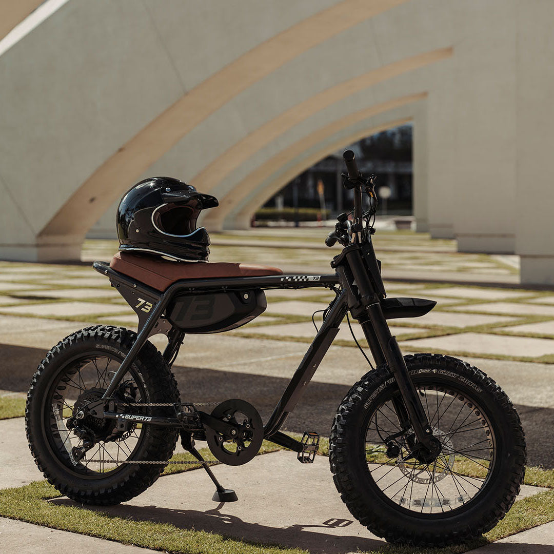Lifestyle image of a parked SUPER73-Z Adventure SE ebike in Palladium with a helmet sitting on top of it