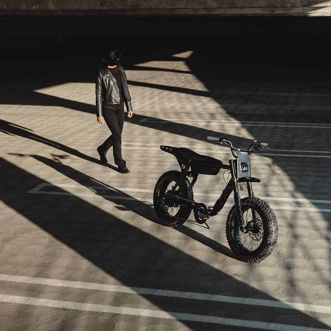 Image of a rider wearing a helmet approaching the SUPER73-Z Blackout SE bike in a parking garage.