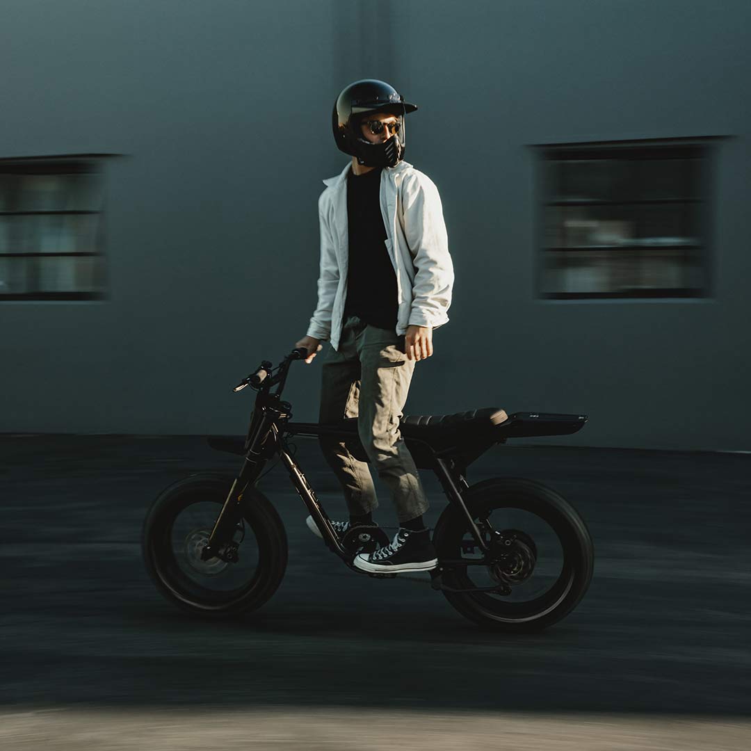Image of a man wearing a helmet and standing on a SUPER73-Z Blackout SE bike.