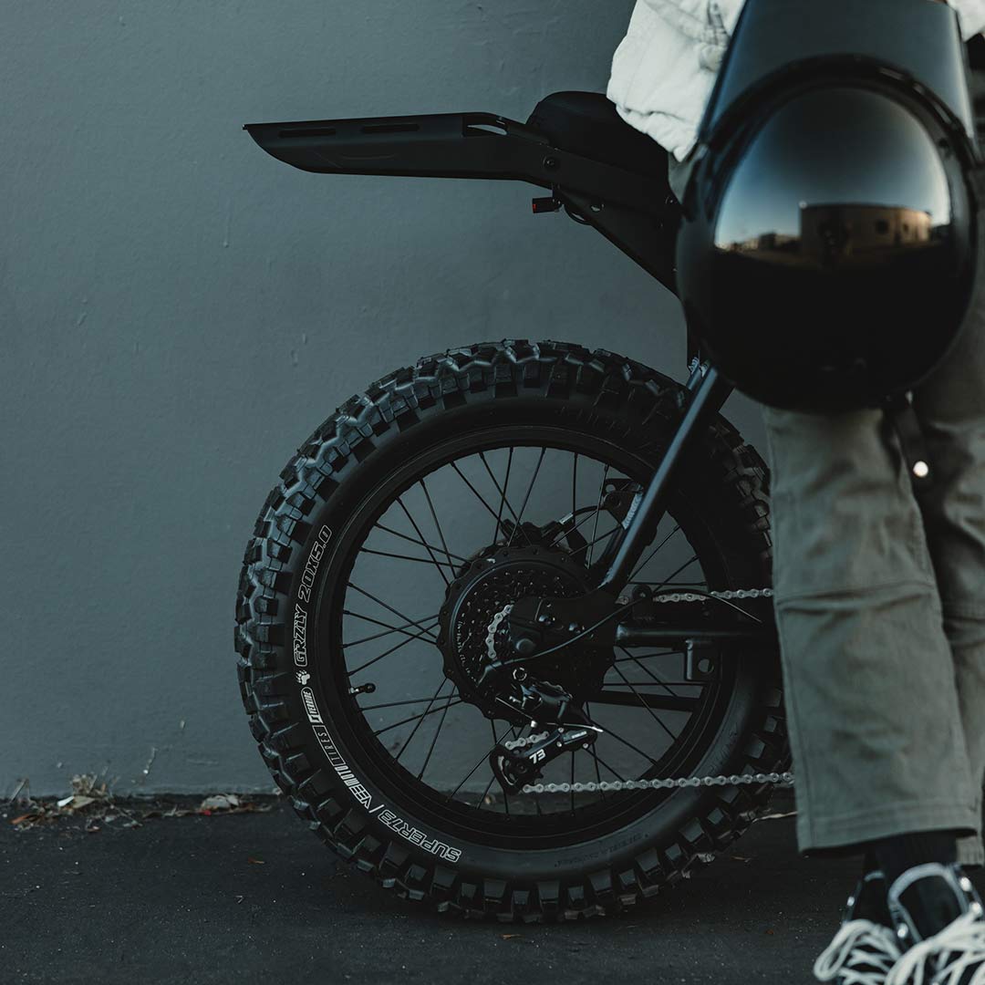 Image of the rear tire and rack of a SUPER73-Z Blackout SE bike with a person leaning against it.