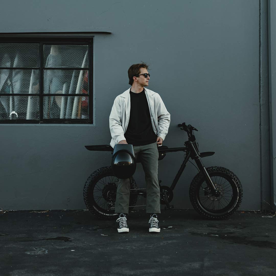 Image of a man standing in front of a SUPER73-Z Blackout SE bike against a gray wall.