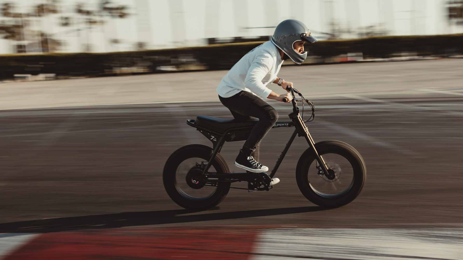 The Super73-ZX ebike throttling down the street with a rider in a helmet