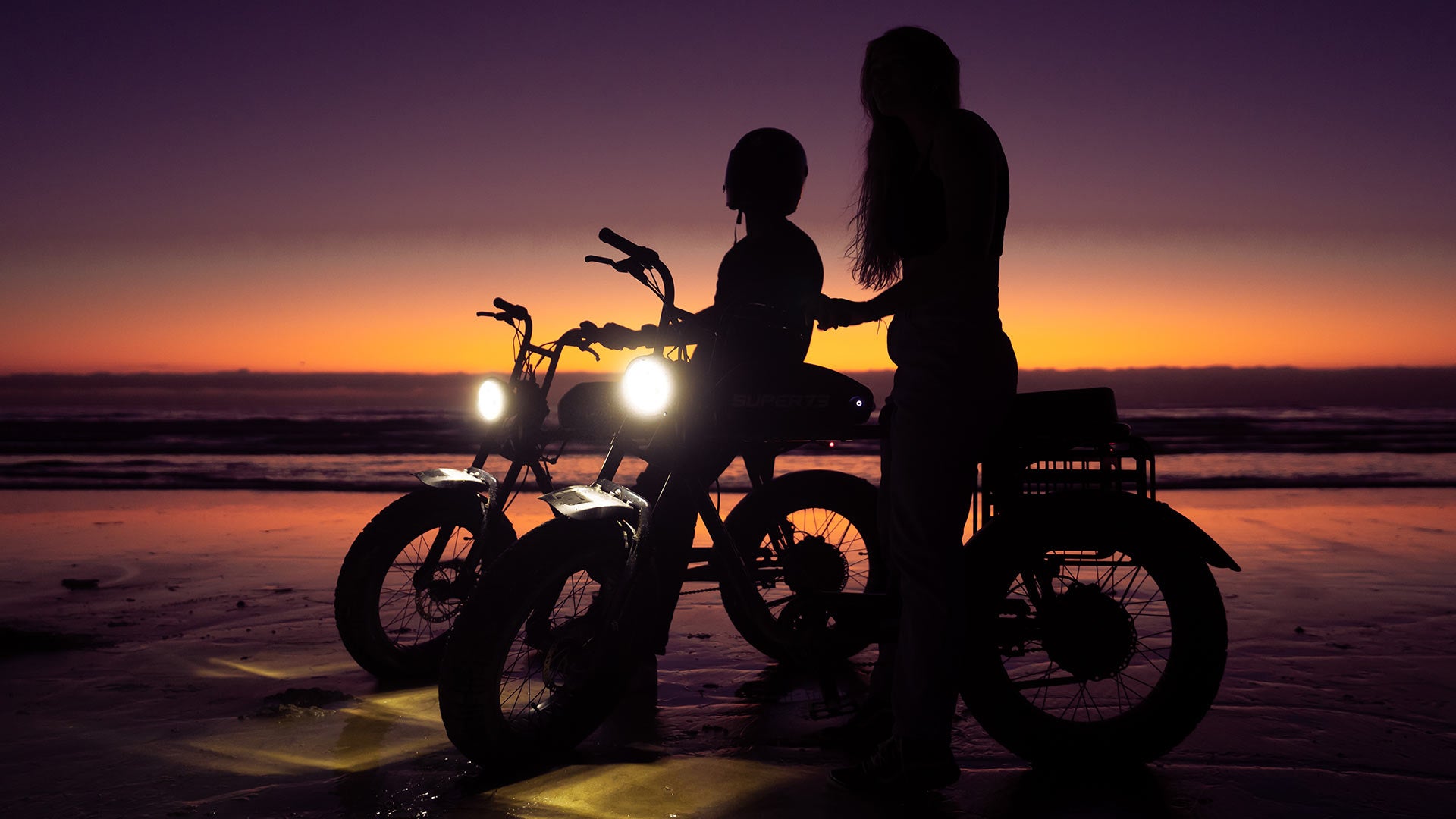 Silhouette of 2 Super73 ebikes parked at beach after sunset