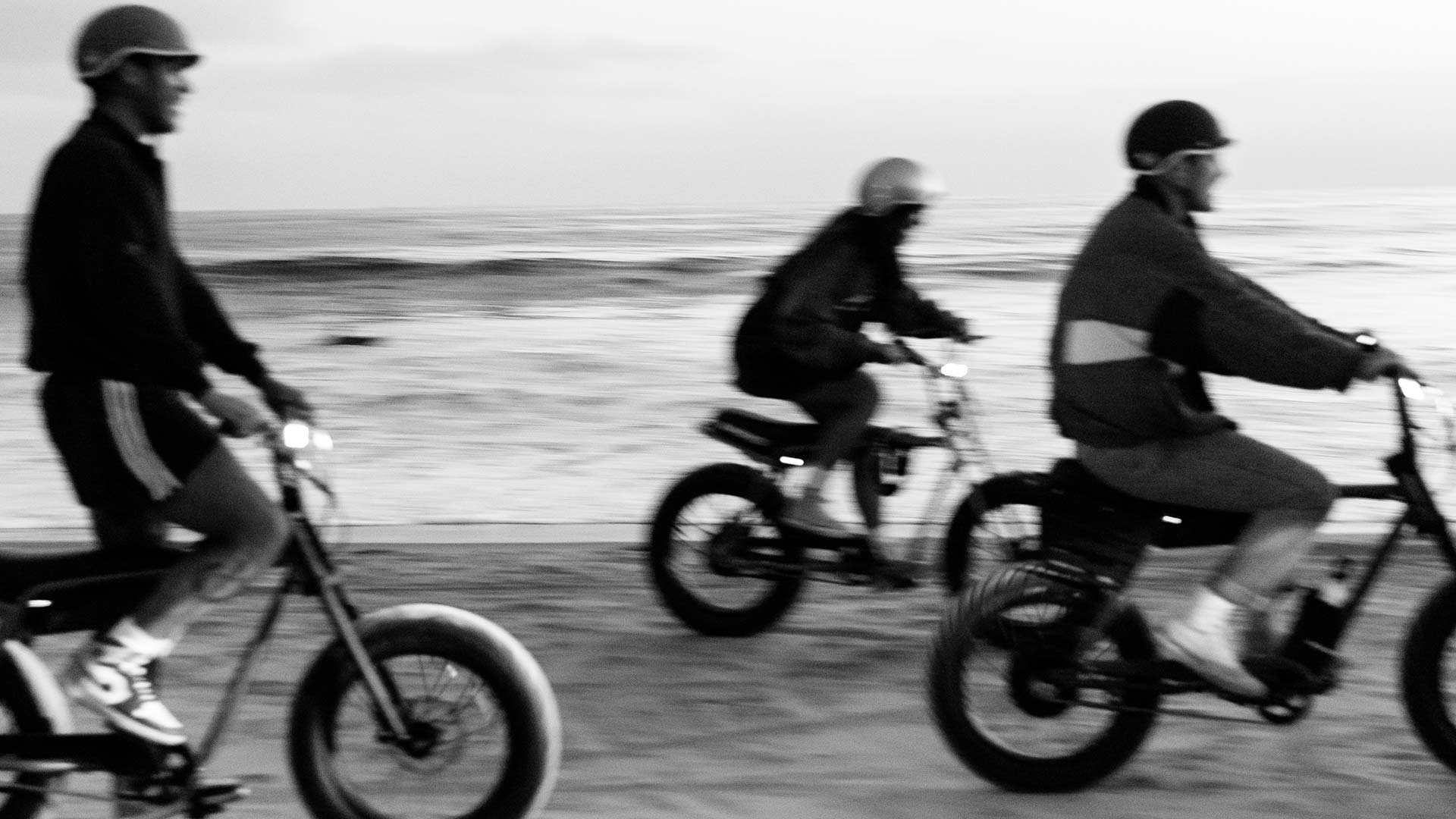 Blurry black and white shot of riders on Super73 ebikes near shoreline
