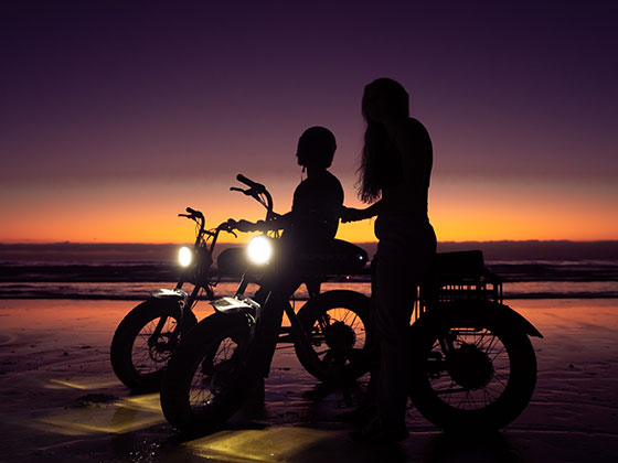 Two people silhouetted in the sunset on Super73 ebikes