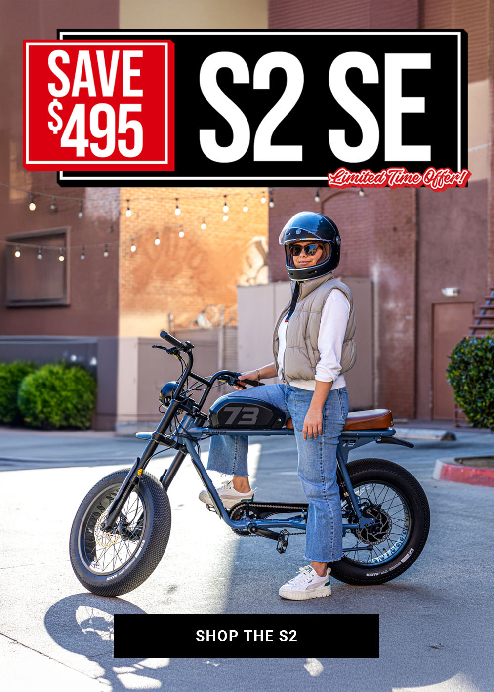 Lifestyle image of a woman wearing a helmet sitting on a SUPER73-S2 SE ebike in Panthro Blue. A text overlay on the image says "Save $495 on the S2 SE for a limited time."