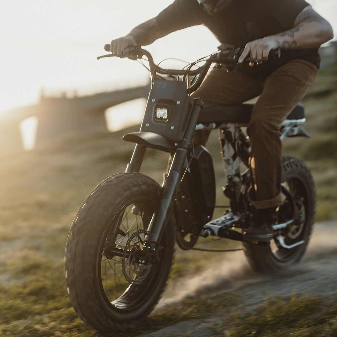Lifestyle image of a rider riding the R Adventure on a dirt path at sunset and wearing a helmet.