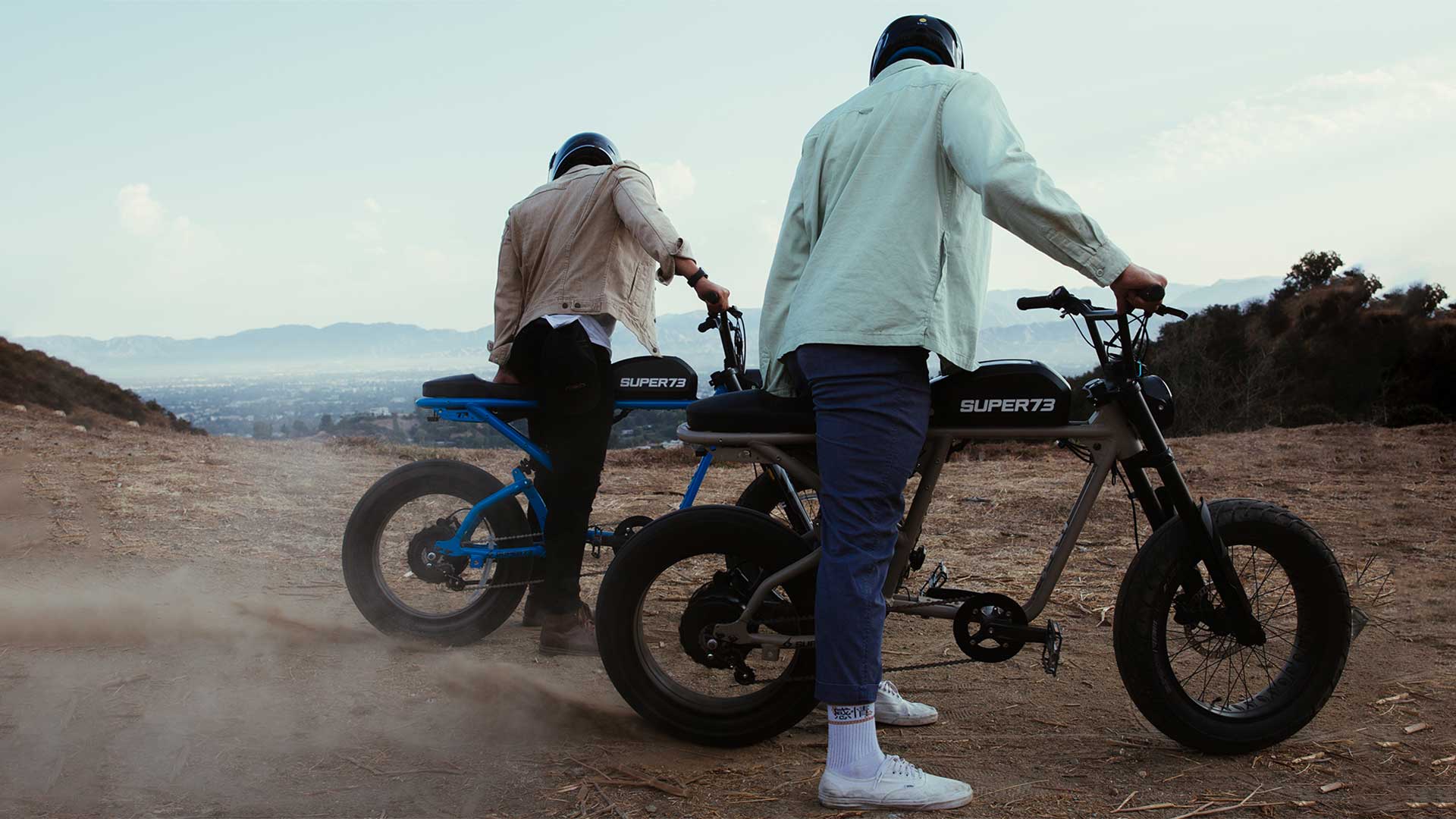 Two men throttling their Super73 ebikes and kicking up dirt