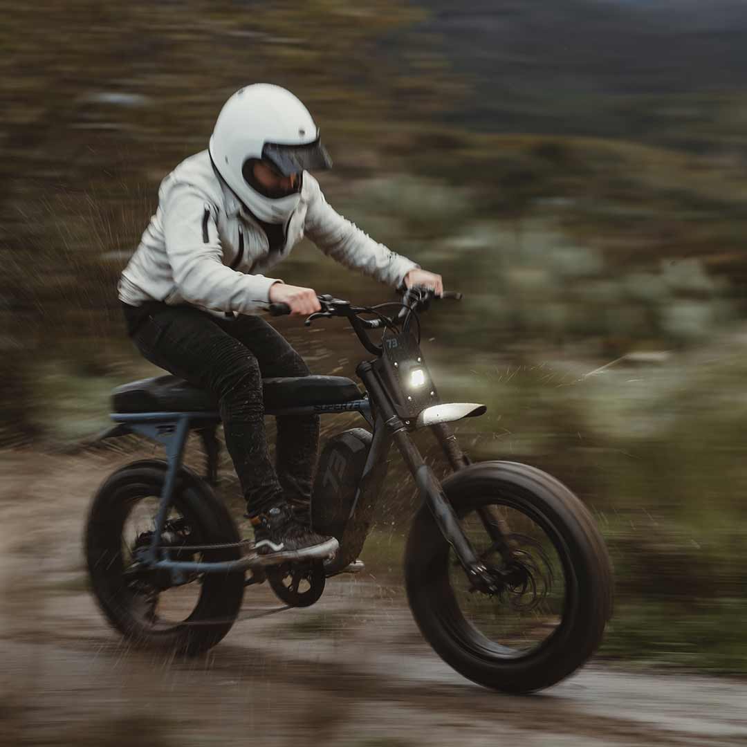 Lifestyle image of a rider riding fast on the S Adventure in the mud and wearing a helmet.