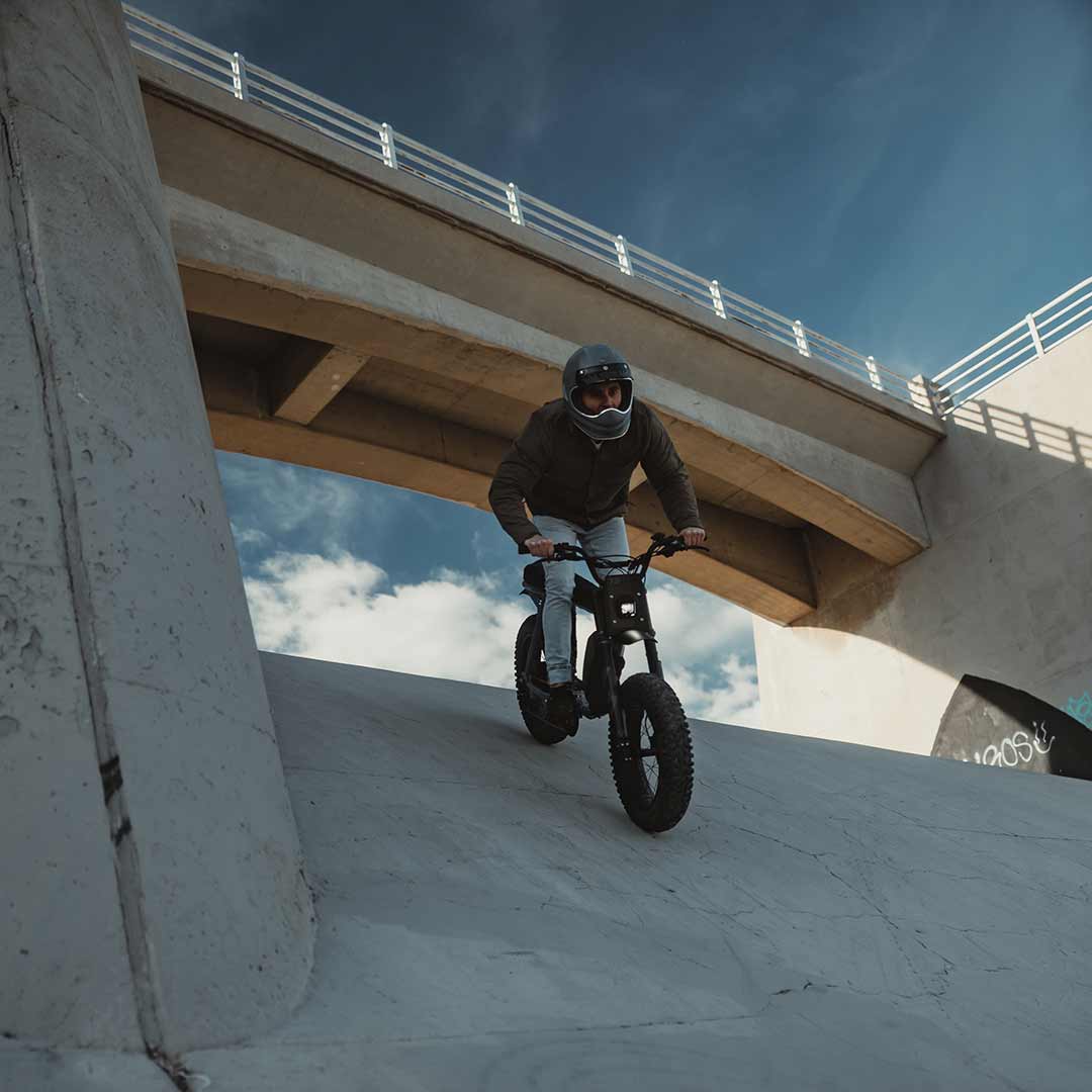 Lifestyle image of a rider riding the S Adventure down a cement slope wearing a helmet.