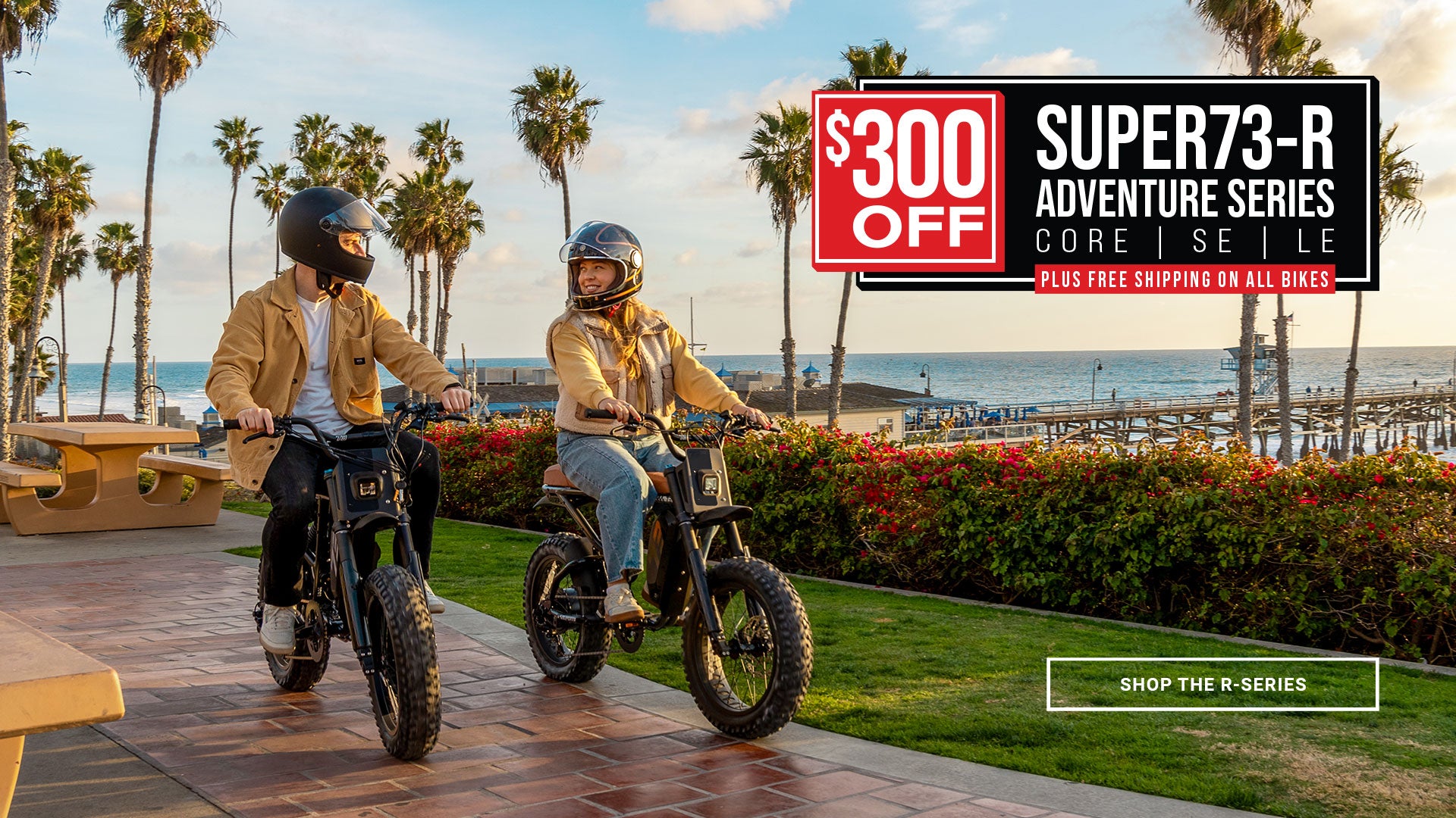 Lifestyle image of a man and woman wearing helmets and riding SUPER73-R Adventure Series ebikes along a brick path with palm trees and a pier in the background. A text overlay outlines the details of the promotion - save $300 on the R Adventure Series Core, SE, and LE models plus get free shipping on all bikes.