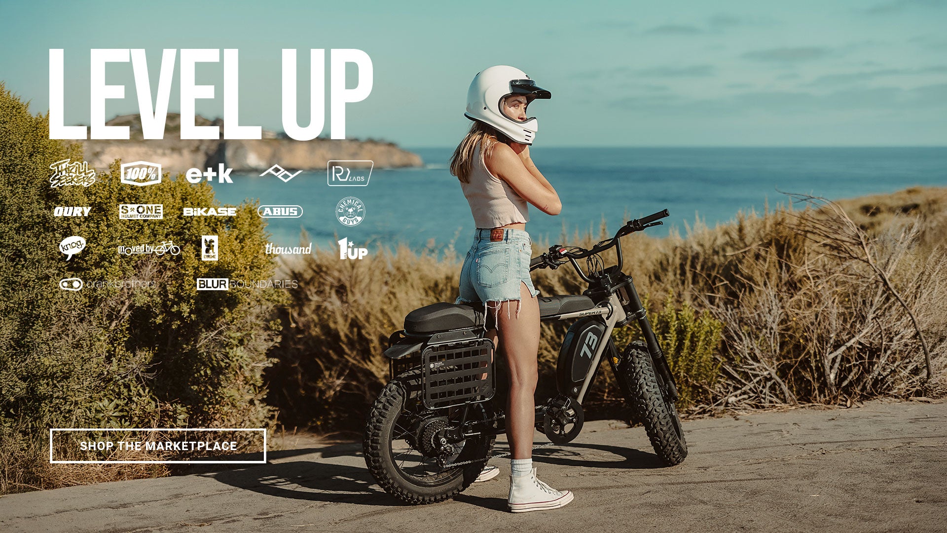 Lifestyle image of a woman wearing a helmet sitting on a SUPER73-S Adventure Series ebike in Sandstorm. 