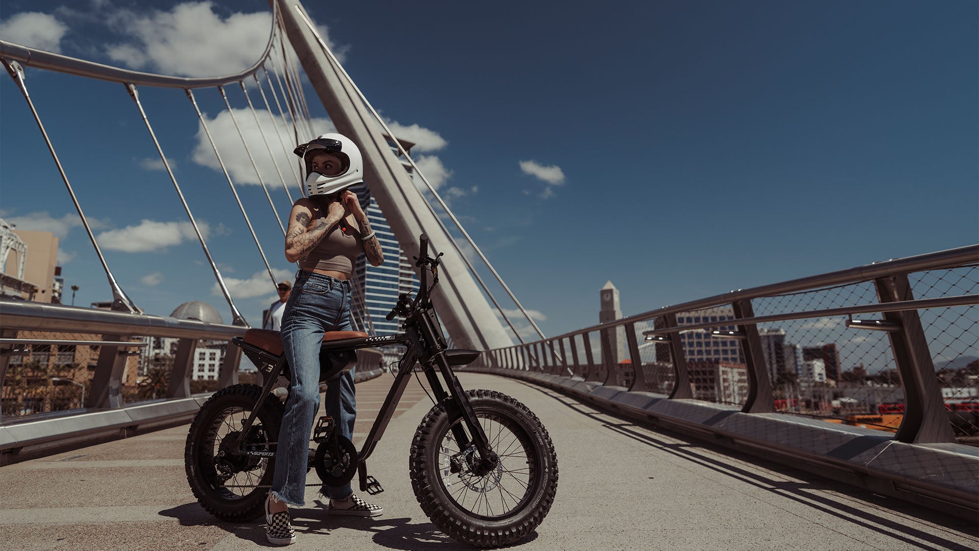 Lifestyle image of a woman in a helmet sitting on the SUPER73-ZX SE ebike in Palldium