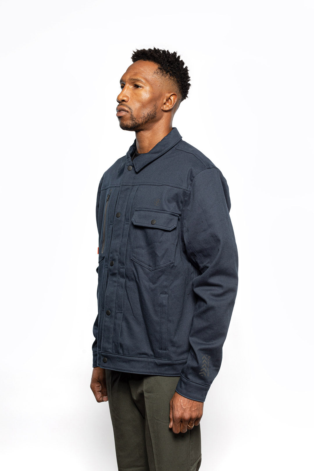 Side view of Male model wearing Anvil Chore Jacket in midnight colorway.