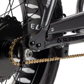 Close up shot of gold chain on bike with a white background.
