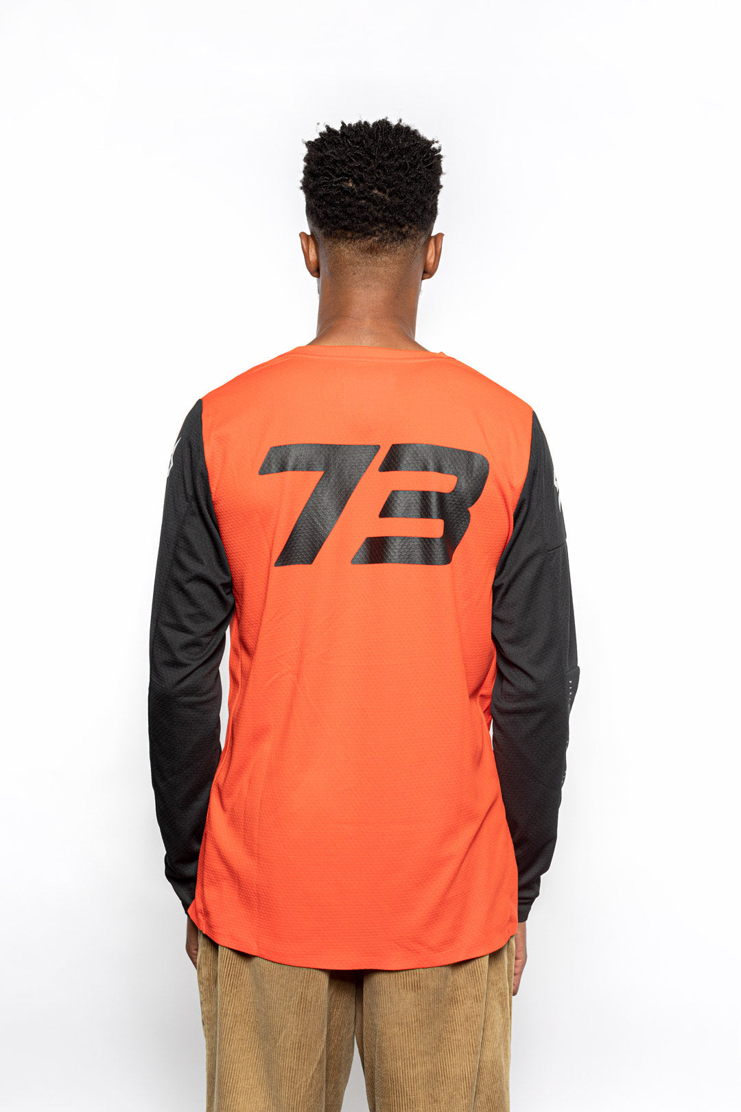 Male model back view of orange Premium long sleeve athletic moto hoon jersey.